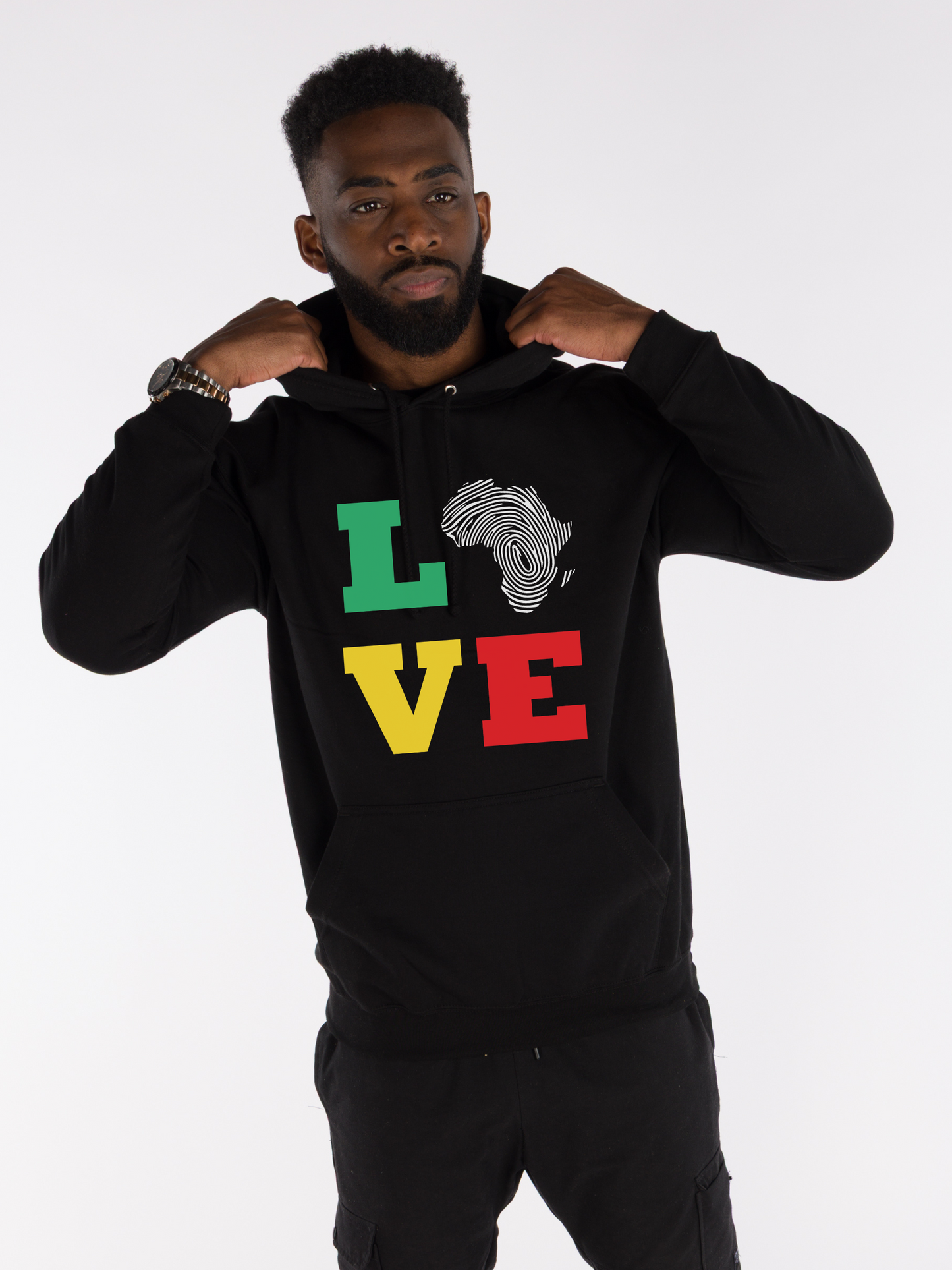 Man wearing unisex black hoodie featuring LOVE design with Africa fingerprint map and Pan-African colors red gold and green. Cultural fashion.