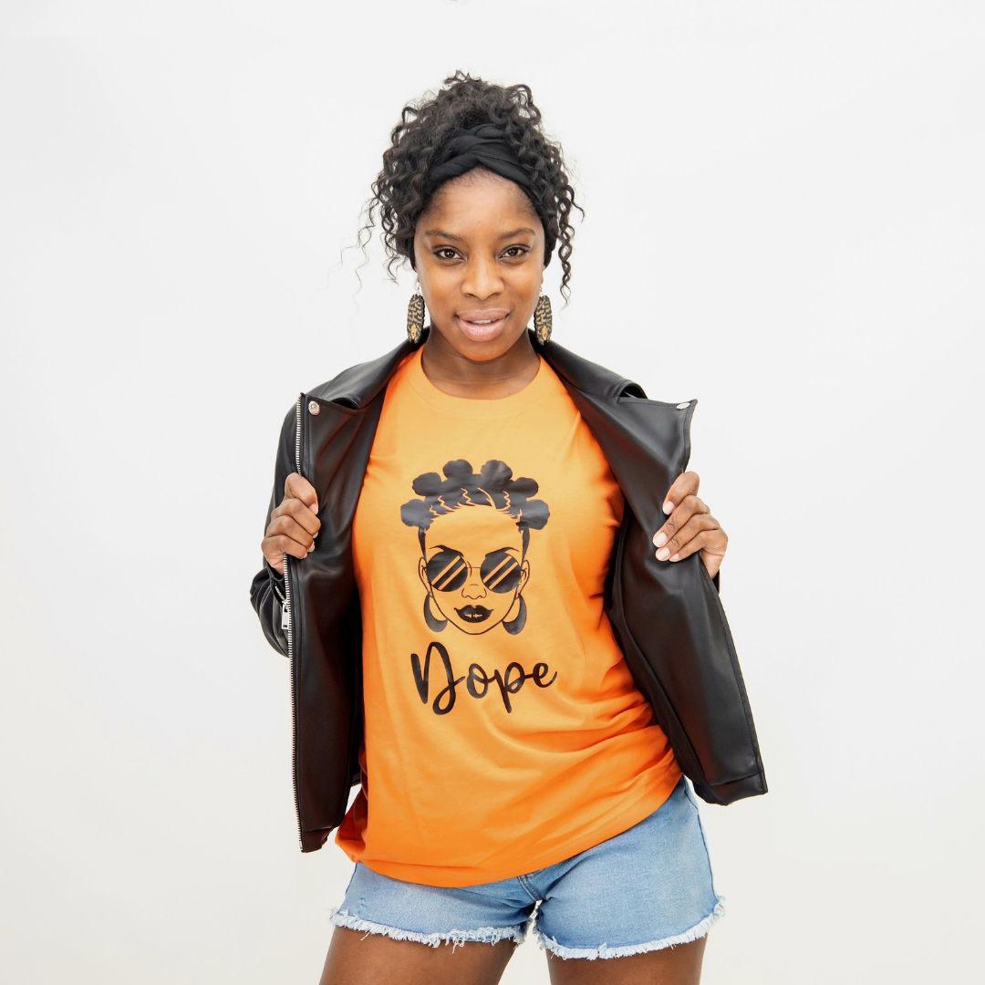 Afro Armour Dope, Bantu knots graphic t-shirt in orange, styled with denim shorts and black leather jacket.